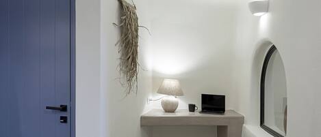 A room with a blue door, a wall-mounted macrame piece, a lamp, a laptop, and a mirror.