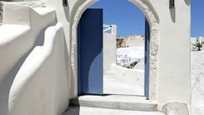 A white-washed building with a blue door and steps leading to an archway. - Acave Santorini Suites (Santorini)