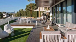A modern outdoor patio with seating, a hanging chair, and a view of the surrounding landscape. - Modern Luxury Villa - 5 brm, heated pool, sea views, gym (Calpe)