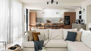 A modern living room with a sofa, coffee table, and a dining area in the background. - Modern Luxury Villa - 5 brm, heated pool, sea views, gym (Calpe)