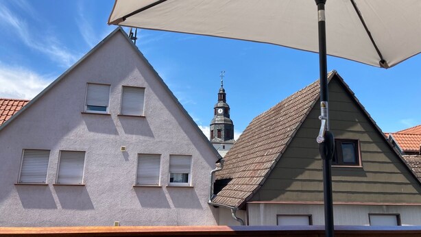 Un edificio con techo inclinado y una torre visible con un reloj.