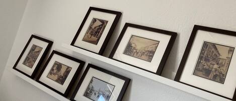 Una pared con una serie de fotografías enmarcadas dispuestas en dos filas sobre un estante blanco.
