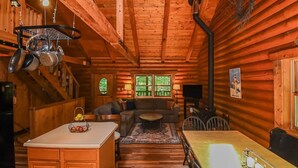 A cozy log cabin interior with a kitchen, dining area, and living room. - Log Cabin Retreat w/ Hot Tub, Game Room, Fire Pit (Swanton)