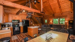 A log cabin interior with a kitchen, dining area, and living room. - Log Cabin Retreat w/ Hot Tub, Game Room, Fire Pit (Swanton)