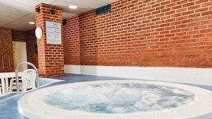 A hot tub in a room with a brick wall, a white ceiling, and a sign on the wall.
