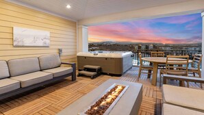Et moderne udendørs loungeområde med sofa, jacuzzi og bålsted.