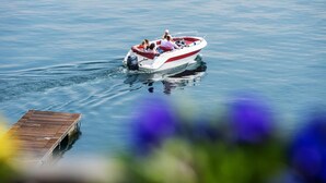 A small motorboat with several people on a calm body of water, docked at a wooden pier. - Studio 2- lake view - Studio Apartment, Sleeps 2 (Oggebbio)