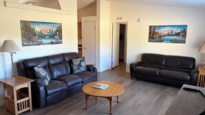 A living room with two leather sofas, a wooden coffee table, and two paintings on the walls. - Hayden’s Green Acres on Big Fall Creek, 3BR 2Bath including River Access (Fall Creek)