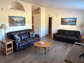 A living room with two leather sofas, a wooden coffee table, and two paintings on the walls.
