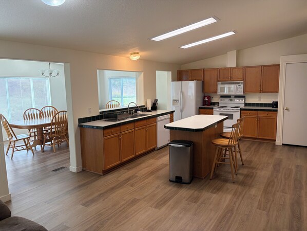 A modern kitchen with wooden cabinets, a central island, and built-in appliances.