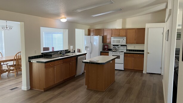 A modern kitchen with wooden cabinets, a central island, a refrigerator, a microwave, and a stove. - Hayden’s Green Acres on Big Fall Creek, 3BR 2Bath including River Access (Fall Creek)
