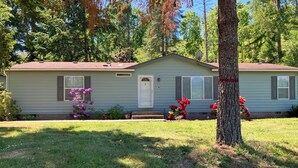 A single-story house with a front porch, a satellite dish, and a small front yard with flowering plants. - Hayden’s Green Acres on Big Fall Creek, 3BR 2Bath including River Access (Fall Creek)