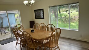 A dining room with a wooden table and chairs, large windows, and a chandelier. - Hayden’s Green Acres on Big Fall Creek, 3BR 2Bath including River Access (Fall Creek)