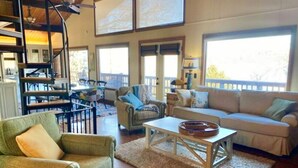 A spacious living area with a high ceiling, a staircase, and a balcony.