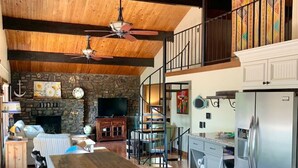 A spacious kitchen with granite countertops, a dining area with a wooden table, and a stone fireplace.