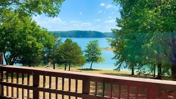 A wooden deck overlooking a lake with trees and a distant mountain range.