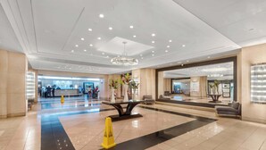 Un hall d’entrée spacieux comprenant un comptoir d’accueil, un lustre et un espace détente avec une table et des chaises.