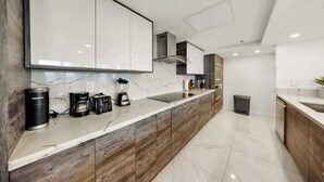 Une cuisine moderne dotée d’un plan de travail en marbre, de meubles en bois et d’un four encastré.