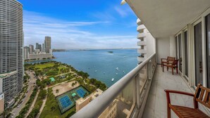 Un balcon avec vue sur un port de plaisance, un court de tennis et des immeubles de grande hauteur.