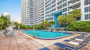 Un hôtel moderne doté d’une piscine sur le toit, de chaises longues et de palmiers.
