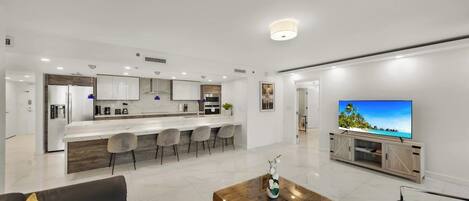 Un espacio habitable moderno con cocina, comedor y un televisor de pantalla plana grande.