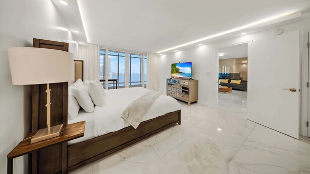 Une chambre d’hôtel moderne avec un grand lit, une télévision et une vue sur la ville.