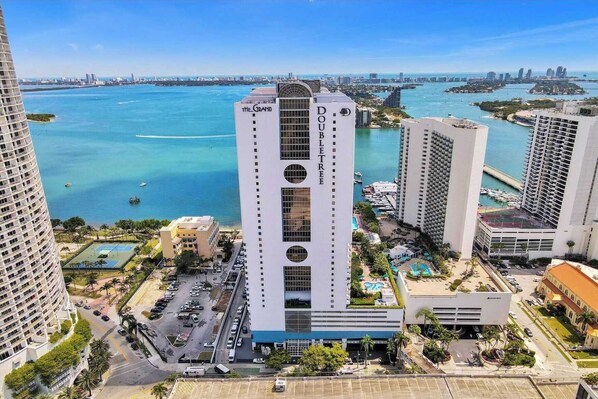 A high-rise hotel with a central atrium, surrounded by a marina and water views.