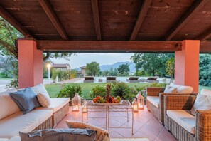 A covered outdoor seating area with wicker furniture and a fruit platter.