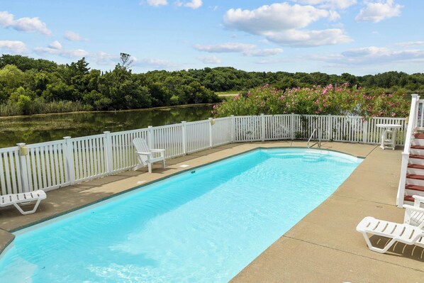 A rectangular swimming pool with a white deck and a white fence.