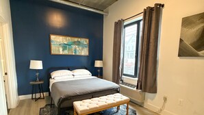 A bedroom with a bed, bedside tables, a bench, a painting, and a window with curtains. - Cozy 2BR Near Airport 4wef (Elizabeth)