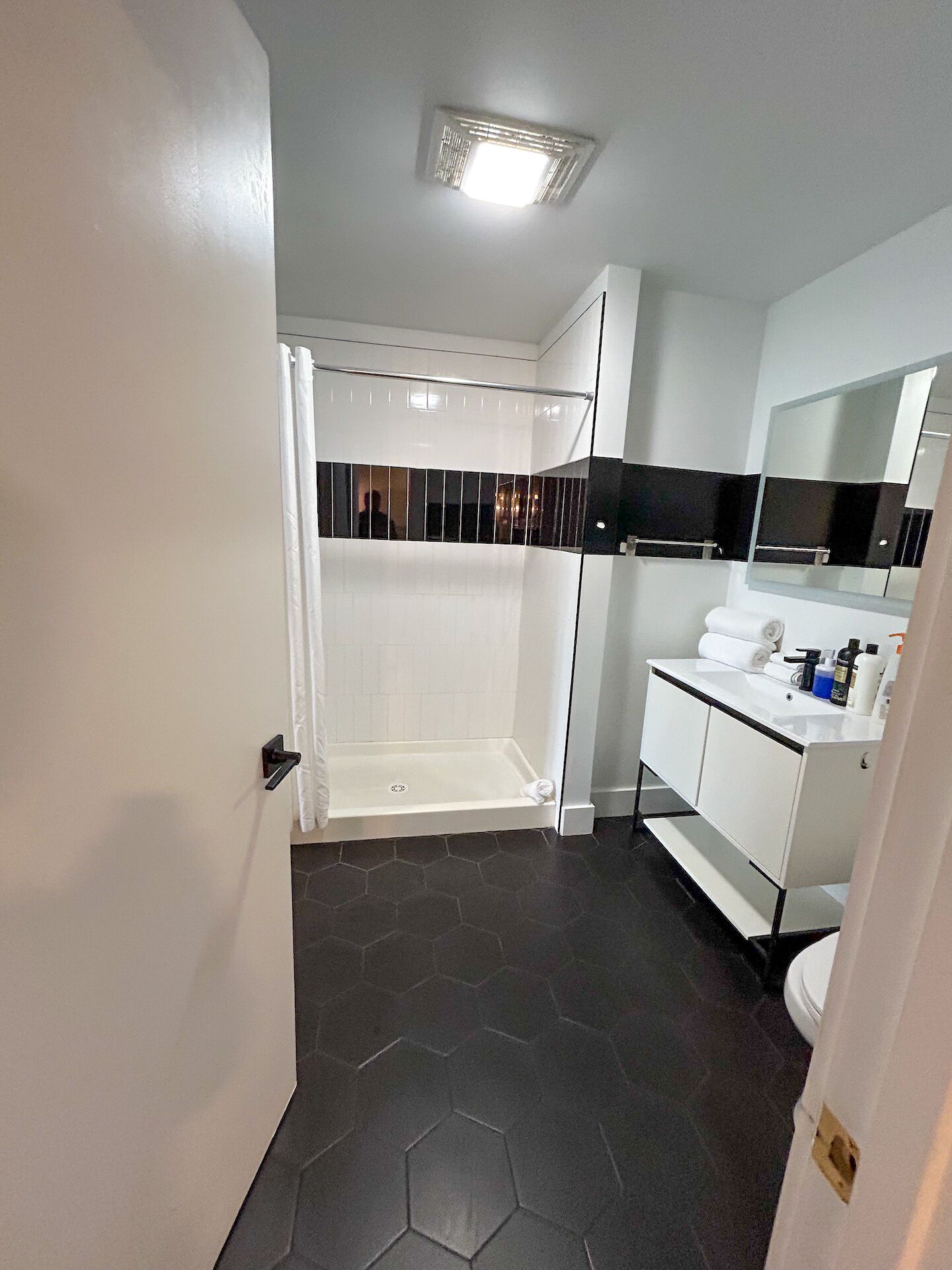 Een moderne badkamer met douche, toilet en wastafel.