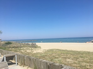 A beach with a wooden fence and a bench.