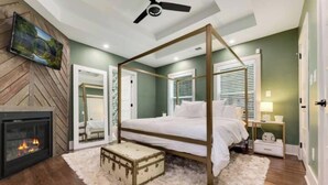 Un dormitorio con una cama con dosel, una chimenea y un ventilador de techo.