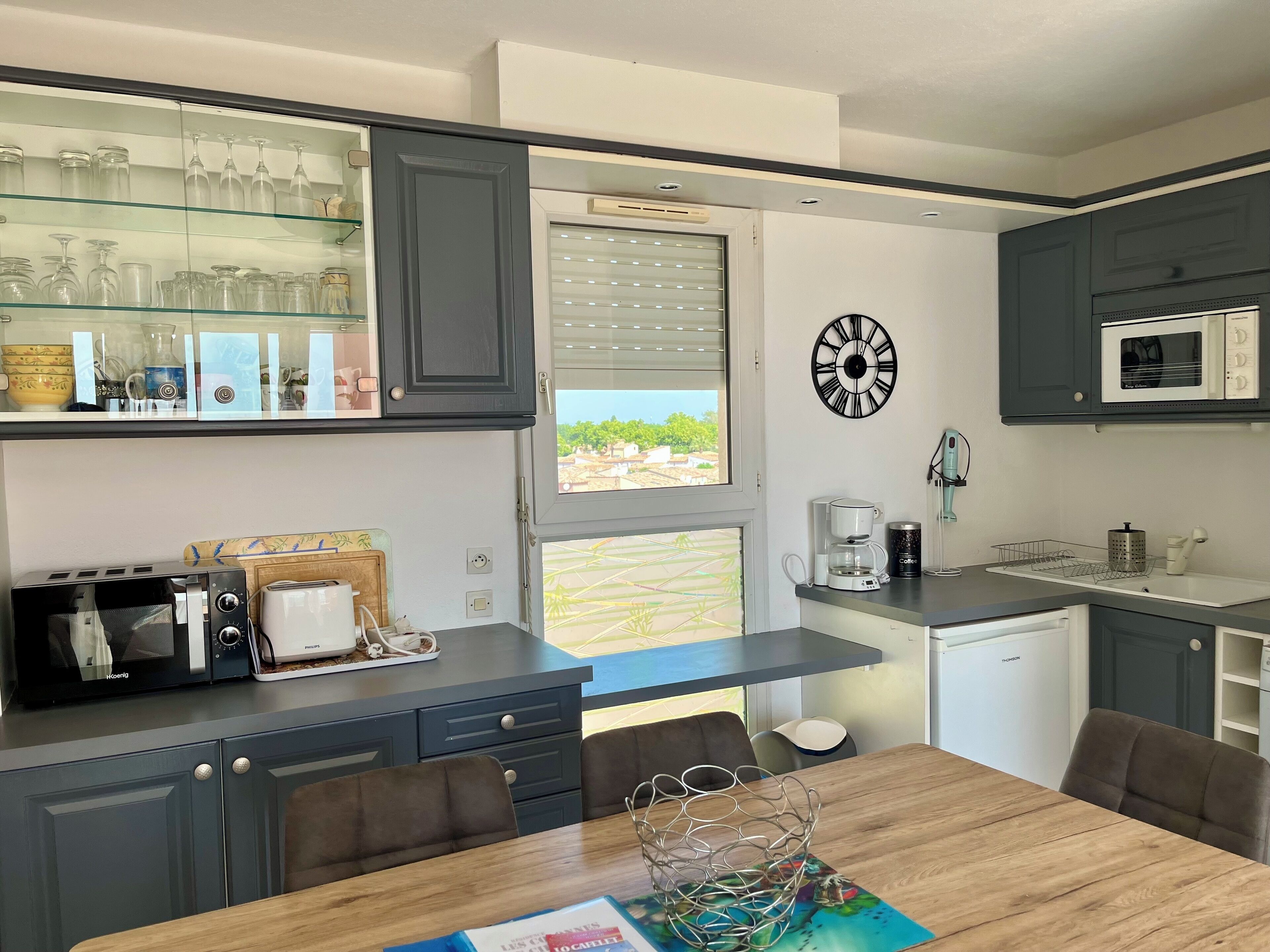 A modern kitchen with a dining area, featuring a microwave, coffee maker, and a view of the outdoors.