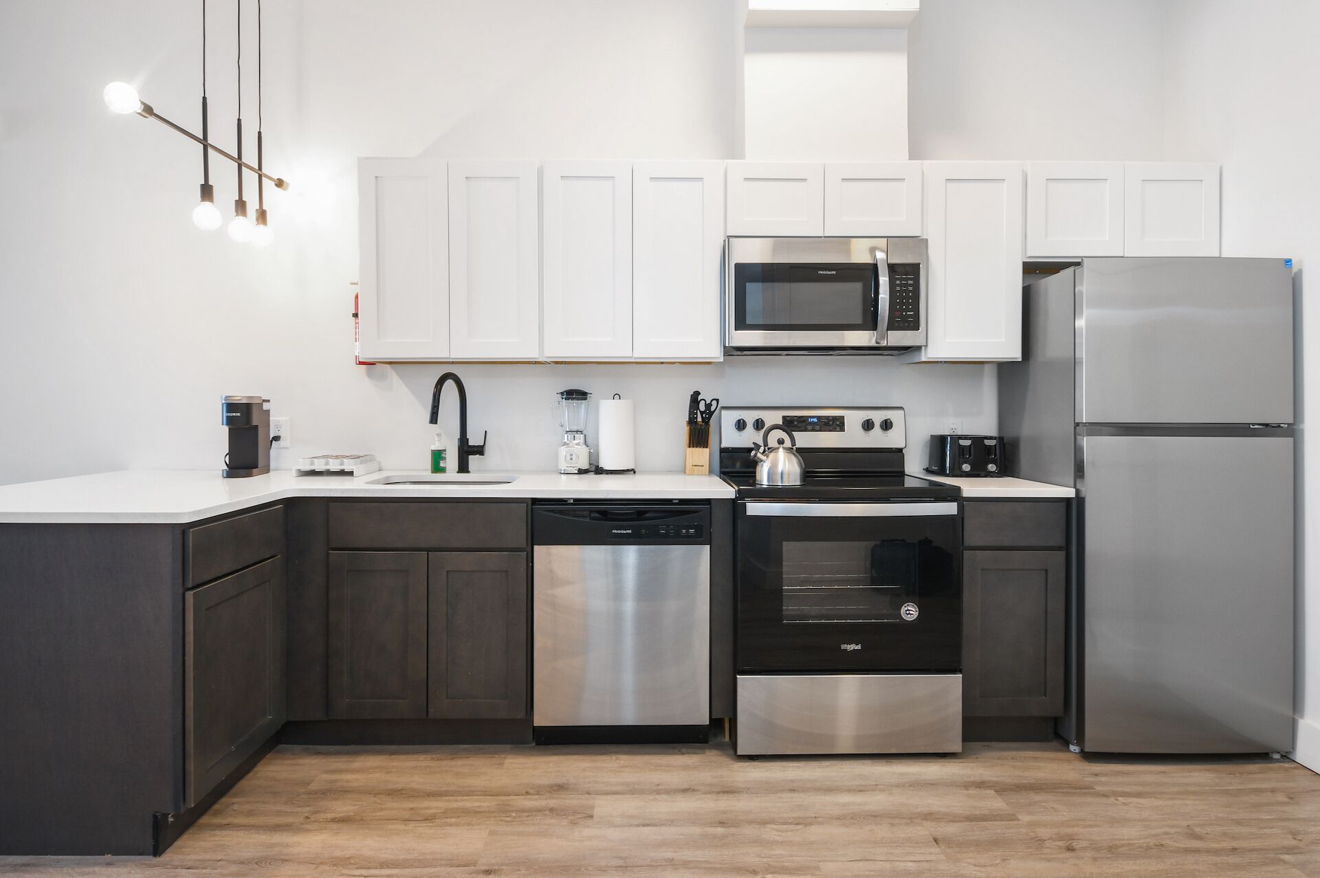 Una cocina moderna con armarios blancos, electrodomésticos de acero inoxidable y piso de madera.