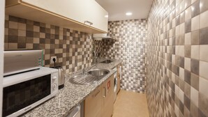 A compact kitchen with a microwave, sink, and washing machine.