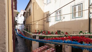 A narrow street with tables and benches set up for outdoor dining, surrounded by buildings with balconies and windows.