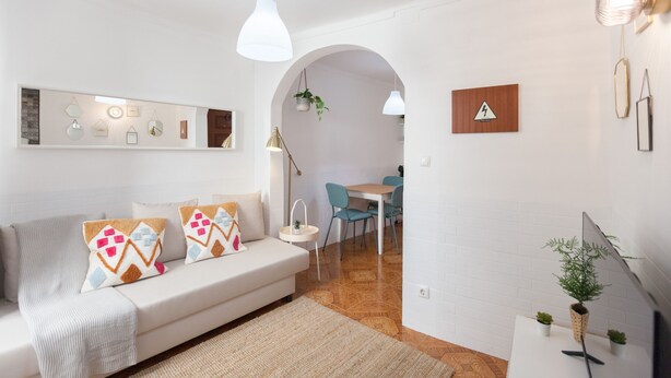 A modern living room with a sofa, a dining area, and a TV.
