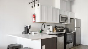 A modern kitchen with white cabinetry, stainless steel appliances, a coffee maker, and a built-in microwave.