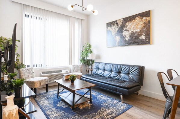 Un salon moderne avec un canapé en cuir, une table basse et un grand tableau abstrait accroché au mur.