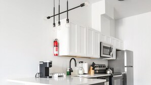 Een moderne keuken met witte kasten, een centraal eiland met krukken, roestvrijstalen apparatuur en hanglampen.