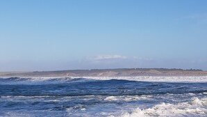 A coastal view with rough sea waves and a distant landmass with cliffs. - Apartment 65B (Thurso)