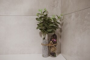 Two clear glass vases with plants and decorative elements against a textured wall.