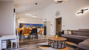 Een moderne woonkamer met een bank, een salontafel en een eethoek met stoelen en een tafel.