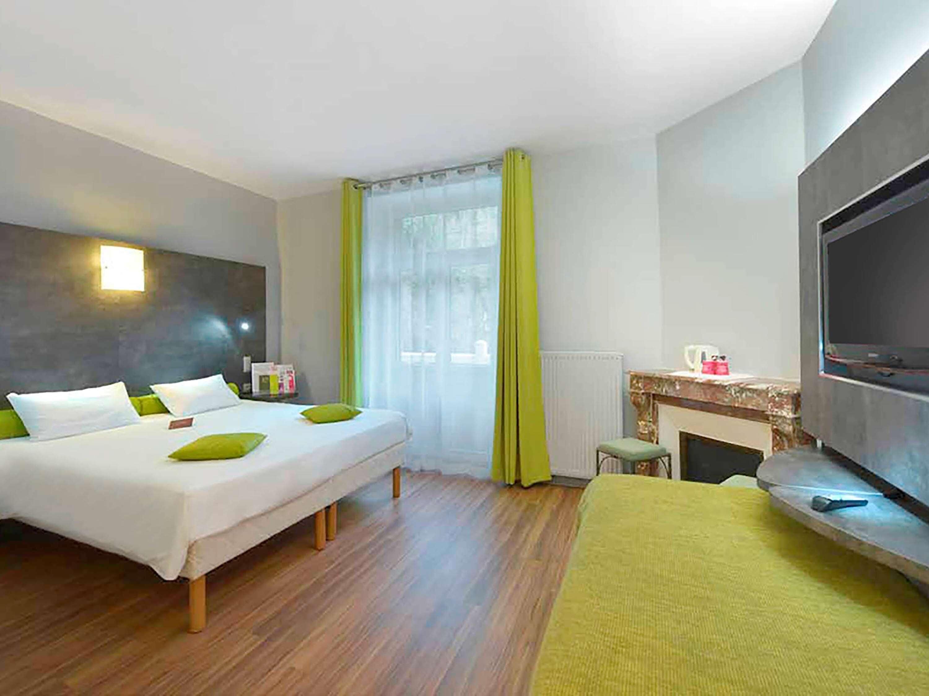 Habitació d'hotel amb llit, televisió, xemeneia i finestra amb cortines.