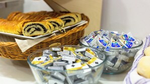 A basket of pastries and a bowl of tea packets. - Minimino hotel (Prague)