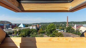 A room with a skylight and a view of a cityscape including buildings and trees. - Minimino hotel (Prague)