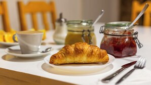 A breakfast setting with a croissant, a cup, a jar of jam, and a bottle of milk on a table. - Minimino hotel (Prague)