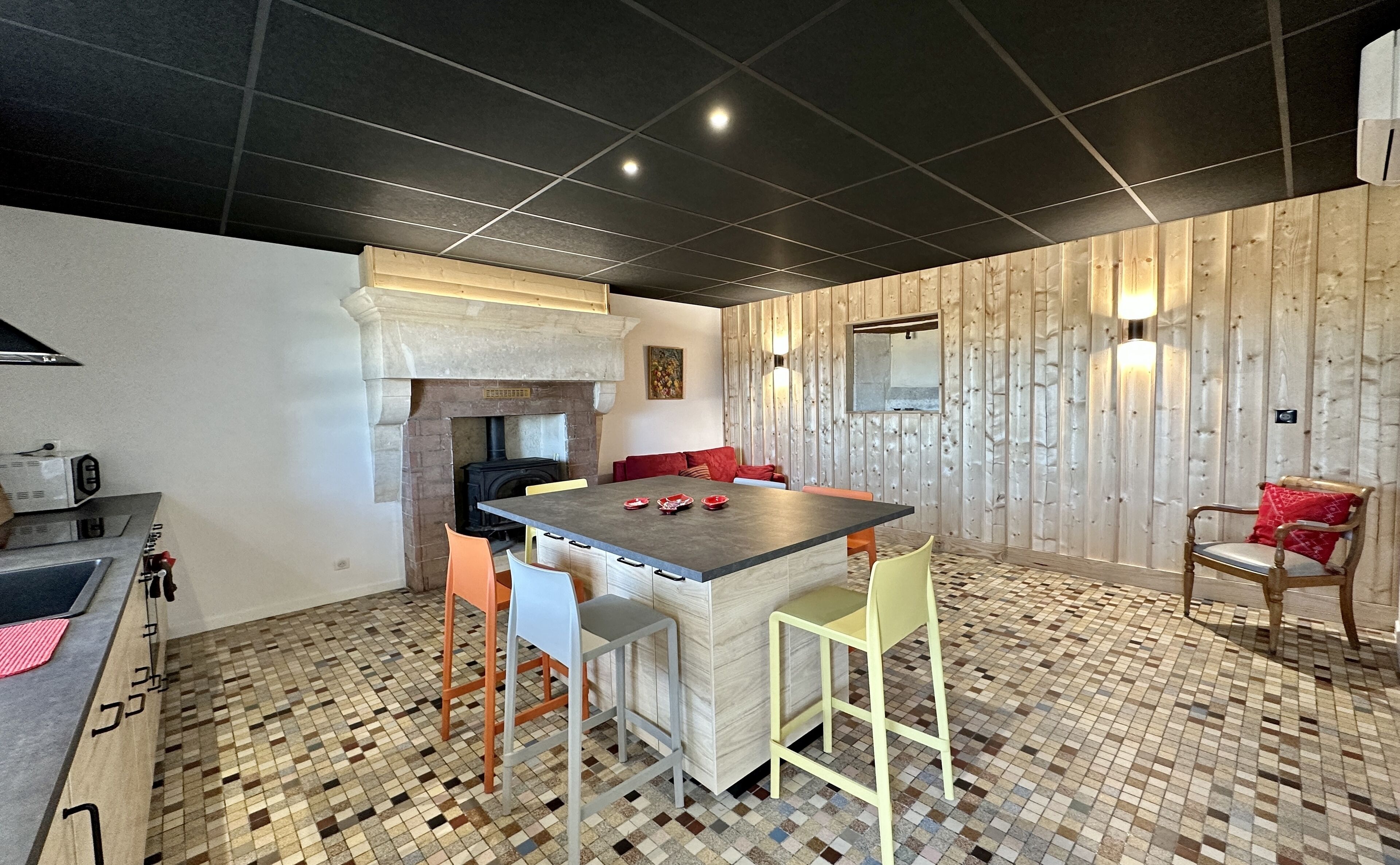A modern kitchen with a central island, a built-in stove, and a dining area with a wooden wall and a bench.