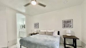 Una camera da letto con un letto, un comodino, una lampada da notte e opere d'arte alle pareti.